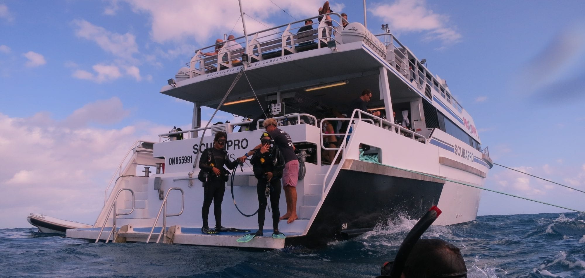 Cairns liveaboard scuba diving - scuba divers prepare to enter the water off the back of the Scubapro boat on the Great Barrier Reef, Queenland